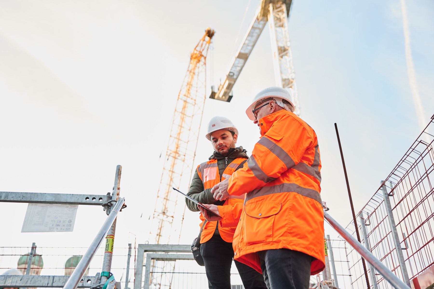 On a rail infrastructure construction site, coordinating with a colleague